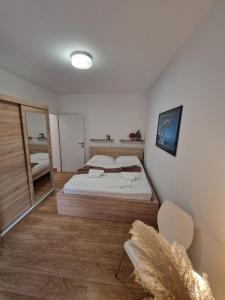een slaapkamer met een bed, een spiegel en een stoel bij Apartment Dome in Biograd na Moru