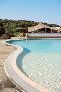 uma piscina com água azul em frente a um edifício em Kirani Resort em Pantelleria