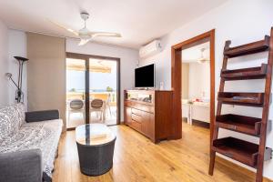 een woonkamer met een bank en een televisie bij Exclusive Penthouse Playa Las Vistas 4 close to the sea and beach, aircondition for a fee, wifi, terrace, heated pool in Playa de las Americas