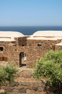 a stone building with an open door and the ocean at Kirani Resort in Pantelleria
