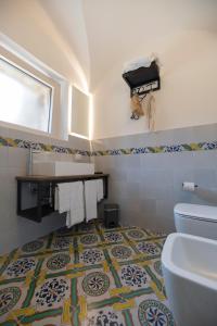 a bathroom with a toilet and a tile floor at Kirani Resort in Pantelleria