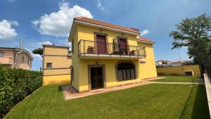 a yellow house with a balcony on a lawn at Guest House Le Vagabonde in Fiumicino