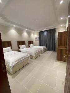 a bedroom with three beds and a window at قاردن وحدات سكنية خاصة in Al Madinah