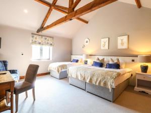 two beds in a bedroom with a desk and a chair at Shorthorn Barn in Norwich