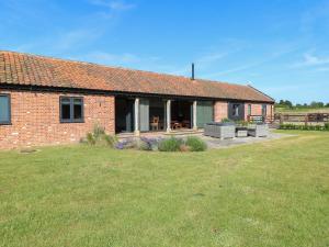 a brick house with a patio and a yard at Shorthorn Barn in Norwich