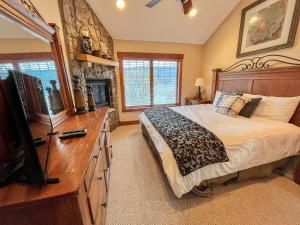 Schlafzimmer mit einem Bett, einem TV und einem Kamin in der Unterkunft Lakefront home with fire pit and dock Near Wisp Resort in McHenry
