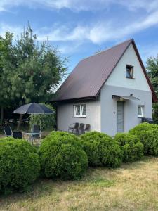 a white house with a roof with chairs and an umbrella at Domek na Żurawiej in Gdańsk