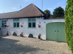 uma casa branca com uma garagem verde em Beautiful Little Bungalow, Indoor Fireplace, & Bar em Ash