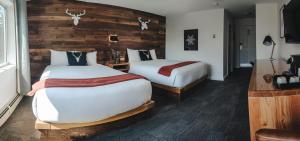 Habitación de hotel con 2 camas y pared de madera. en Heather Mountain Lodge, en Golden