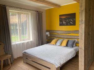1 dormitorio con cama y pared amarilla en Vējavas, en Svettsiyems