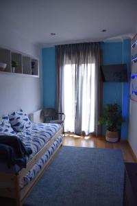 Habitación azul con cama y ventana en Casa Punta Balea, en el centro, en Cangas de Morrazo