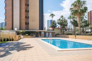 een zwembad met palmbomen en gebouwen bij Gemelos 23 Apartment 5-A Levante Beach in Benidorm