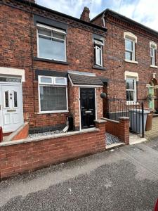 a brick house with a cat sitting outside of it at Bright & Central Home in Church Coppenhall