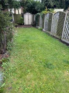 um quintal com uma cerca e um quintal com relva verde em Bright & Central Home em Church Coppenhall