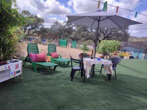a table and chairs with an umbrella in the grass at Casa Rural Paraiso de Emilia in La Aulaga
