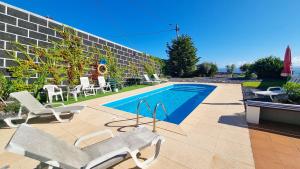 a swimming pool with two chairs and a bench next to a building at Loreto Rose, Panoramic Ocean and Mountain View in Arco da Calheta +20 photos