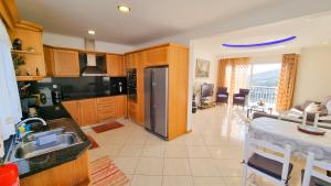 a kitchen with a stainless steel refrigerator and a living room at Loreto Rose, Panoramic Ocean and Mountain View in Arco da Calheta