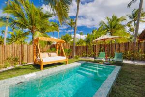 a pool with a swing and a bed next to a fence at Reserva Jacumã Boutique - Trancoso in Trancoso