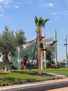 un parque infantil con una palmera y un tobogán en Résidence Le Vizir Center Rez de jardin, en Marrakech