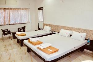 Cette chambre comprend deux lits, une table et des chaises. dans l'établissement Hotel Mangalam, à Kurandvād