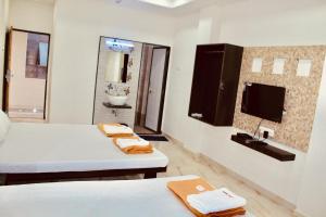 een kamer met 2 bedden en een badkamer met een wastafel bij Hotel Mangalam in Kurandvād