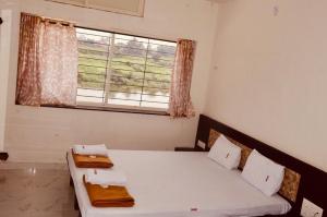 a bedroom with a white bed and a window at Hotel Mangalam in Kurandvād