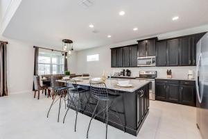 a kitchen with black cabinets and a kitchen island with chairs at BSV1529 - Luxury 7 Bedroom 5 Bathroom Villa in the Desirable Solara Resort in Kissimmee