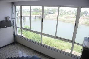 a room with large windows looking out at a river at Hotel Mangalam in Kurandvād