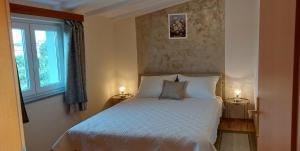 a bedroom with a bed with two lamps and a window at Apartmani Diva in Malinska