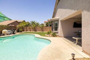 a swimming pool in a yard next to a house at AZ Sun Palm Retreat w/optional Private Heated Pool in Surprise