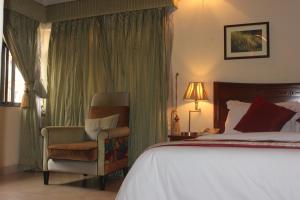 a bedroom with a bed and a chair and a bed and a window at Carlson Hotel, Osborne Foreshore Phase 2, Ikoyi in Lagos