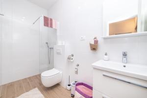 a white bathroom with a toilet and a sink at Lakeview Apartments in Ploče +63 photos
