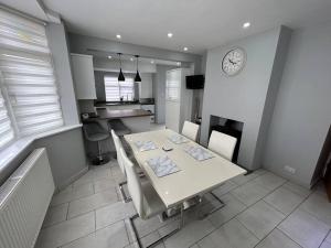 a kitchen with a white table and a clock on the wall at Fresh & Spacious House in Rhyl