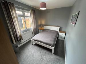 een kleine slaapkamer met een bed en een raam bij Fresh & Spacious House in Rhyl
