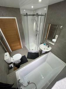 a bathroom with a tub and a toilet and a shower at Fresh & Spacious House in Rhyl