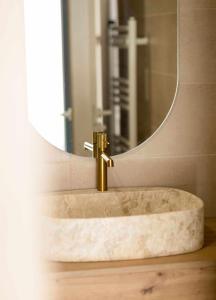 lavabo con grifo de oro frente a un espejo en Can Candiu Establecimiento de 2 casas enteras, en Vall-Llobrega