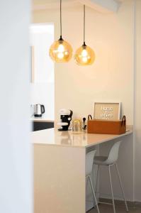 uma cozinha com um balcão branco e duas luzes em Can Candiu Establecimiento de 2 casas enteras em Vall-Llobrega