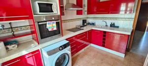 a kitchen with red cabinets and a washing machine at CASA EN CAMPO DE GOLF CERCA DE LA PLAYA in Jerez de la Frontera