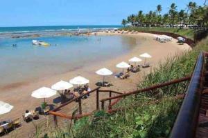a beach with umbrellas and people sitting on the beach at Nannai Residence - Apartamento Duplex in Porto De Galinhas