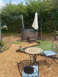 a patio with a grill and a table and chairs at Close to Nature Easy to Find shepherd's hut in North Molton