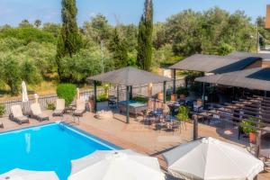 an outdoor pool with umbrellas and tables and chairs at Nikos Villas in Kavos