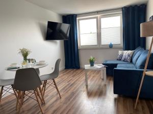 a living room with a blue couch and a table at Apartamenty Dostoja in Władysławowo