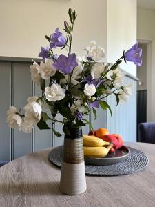 un vase rempli de fleurs violettes et blanches sur une table dans l'établissement Nisterlo Guesthouse, à Nistelrode