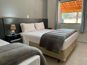 1 dormitorio con 2 camas y ventana en Santana's Ranch, en São Pedro