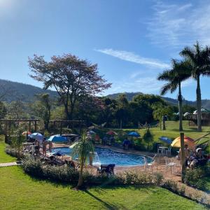 uma piscina com guarda-sóis e pessoas sentadas à sua volta em Santana's Ranch em São Pedro