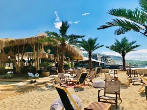 a beach with chairs and umbrellas and palm trees at Supreme appartment in Balchik