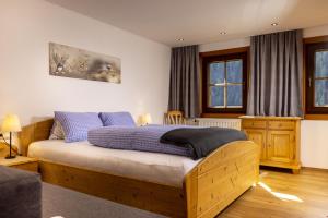 a bedroom with a wooden bed with blue pillows at Haus Arnika in Sankt Jakob in Defereggen