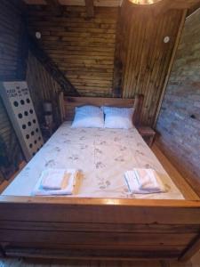 una cama de madera con 2 almohadas encima en Vikendica Una en Kostajnica