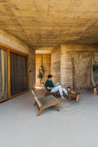 a woman sitting in a chair on a porch at Paradero Todos Santos - Exclusive experiences included in Todos Santos