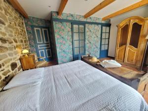 1 dormitorio con 1 cama grande y pared de piedra en Le quartier d'hiver, en Cléden-Cap-Sizun